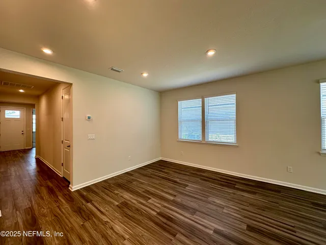 an empty room with windows & cabinet