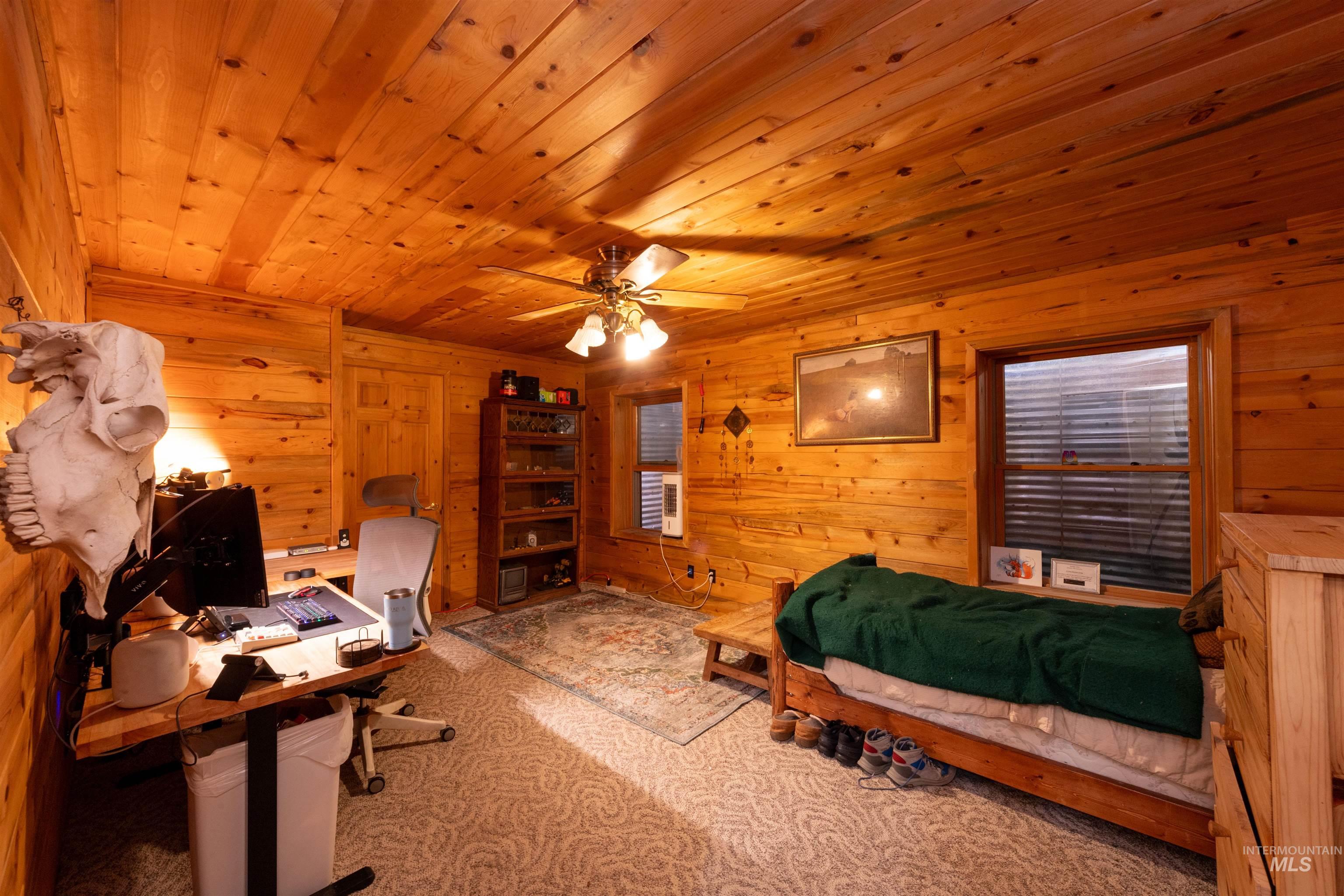 9885 Challis Creek Road Challis, ID 83226 - Photo 30 of 48 Carpeted bedroom featuring an office area, wood walls, wood ceiling, and ceiling fan