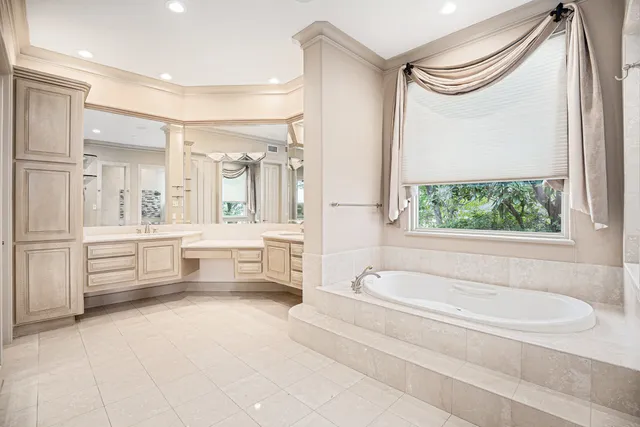 a spacious bathroom with a granite countertop sink a mirror a bathtub and next to a window