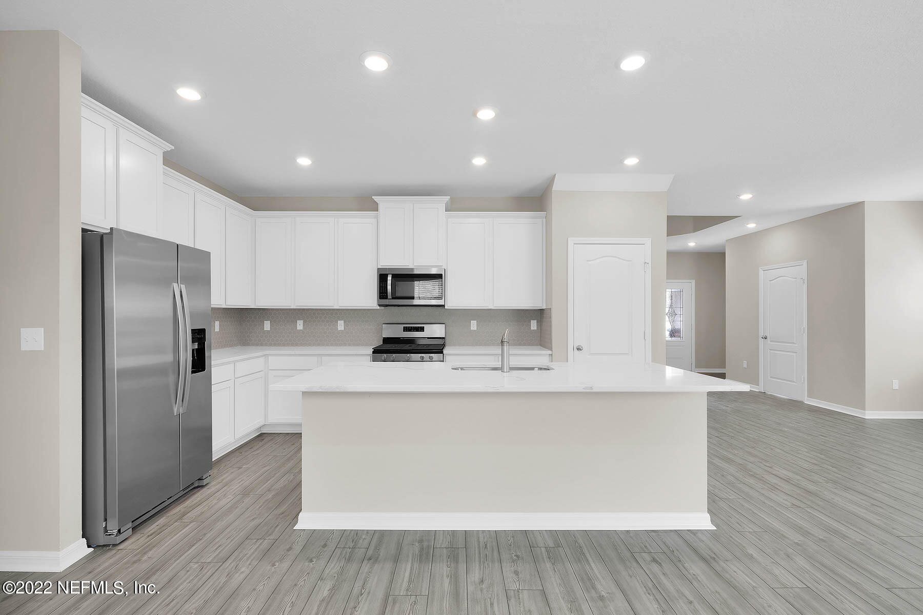 486 Falcon Ridge Road St. Augustine, FL 32084 - Photo 5 of 12 a large kitchen with stainless steel appliances a sink a refrigerator and a stove top oven with wooden floor