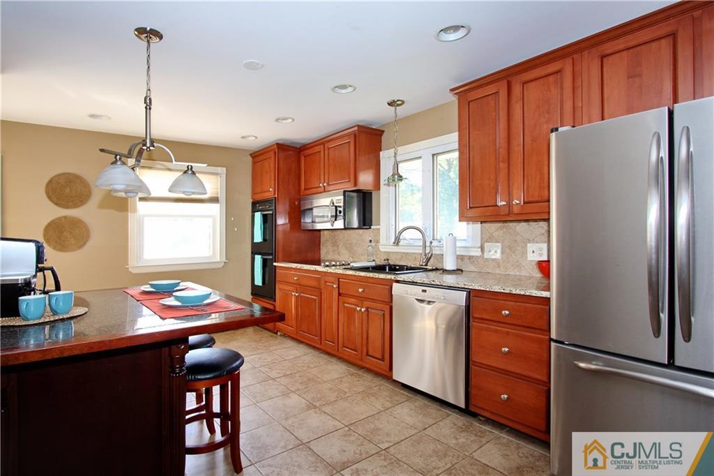 60 Morningside Road Colonia, NJ 07067 - Photo 8 of 21 a kitchen with stainless steel appliances granite countertop a refrigerator a sink dishwasher a dining table and chairs with wooden floor