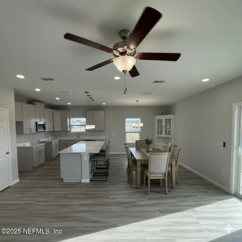 a large kitchen with kitchen island a sink dishwasher a refrigerator and a stove with wooden floor