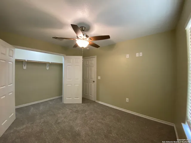 an empty room with a ceiling fan and a window