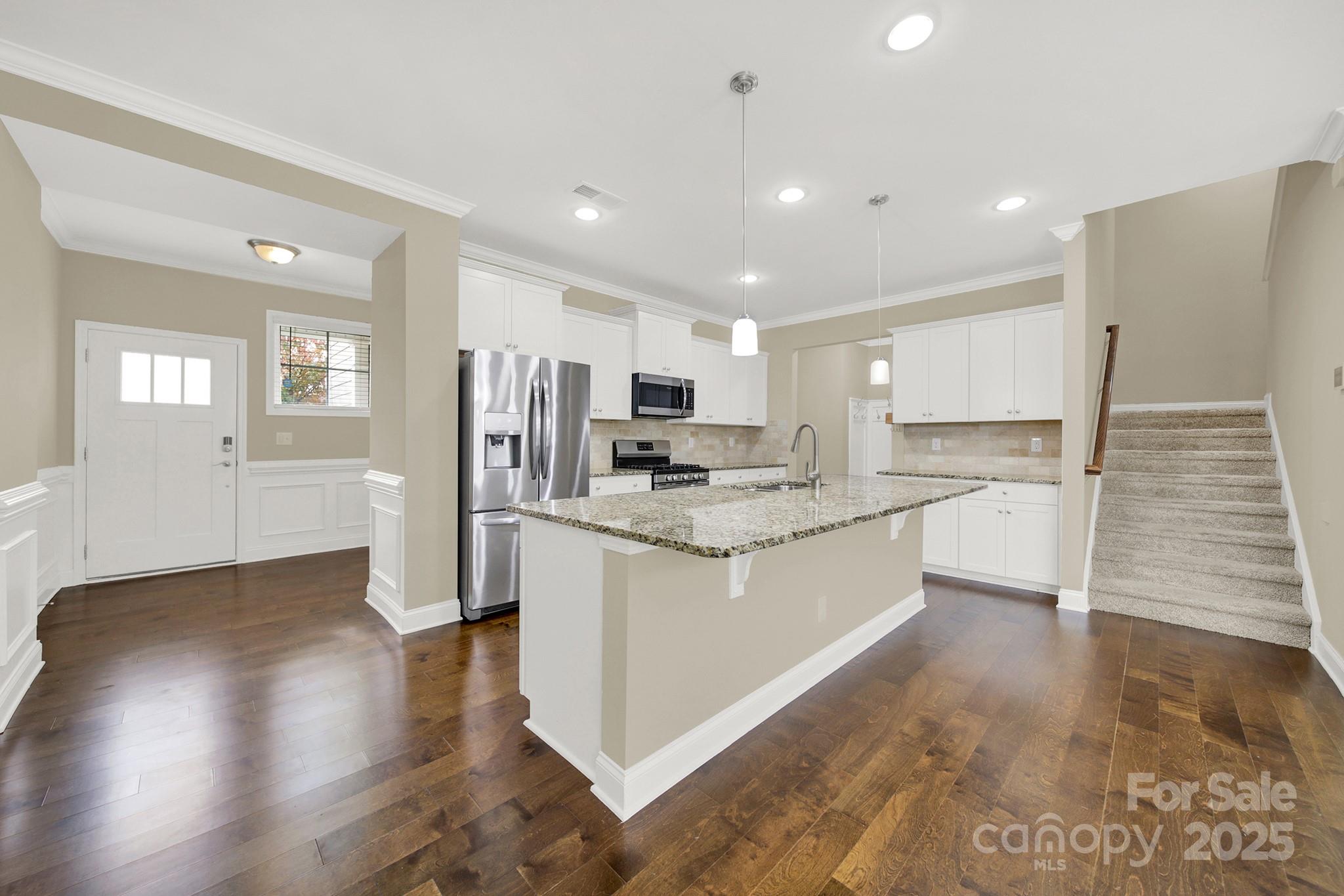 2471 Palmdale Walk Drive, Unit 107 Fort Mill, SC 29708 - Photo 5 of 30 a large kitchen with a center island wooden floor stainless steel appliances and windows