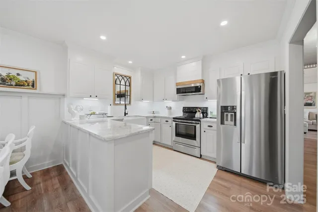 a kitchen with stainless steel appliances white cabinets and a stove top oven