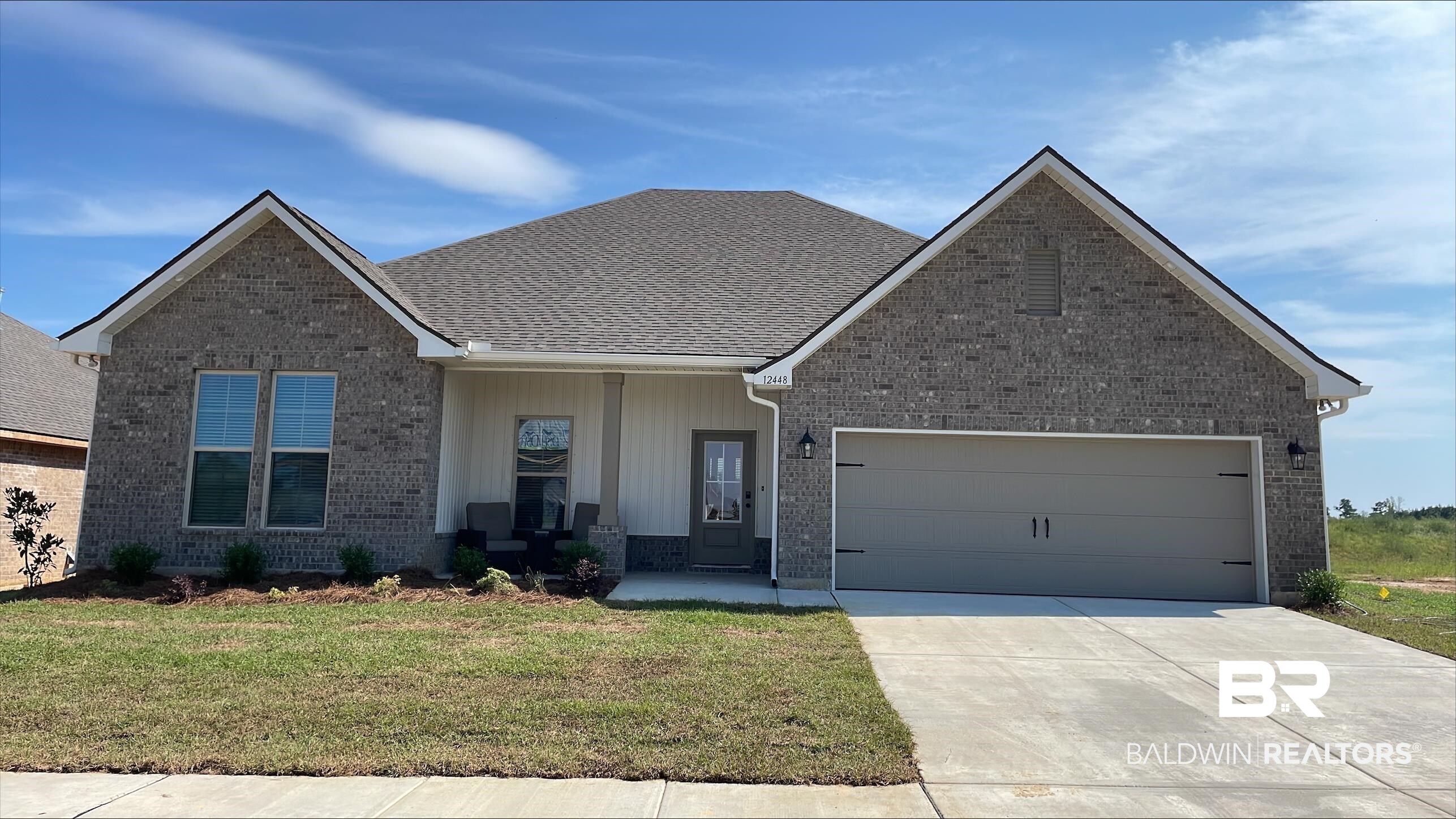 12448 Wagner Avenue Daphne, AL 36527 - Photo 1 of 3 View of front facade with covered porch, a garage, a front lawn, brick siding, and driveway