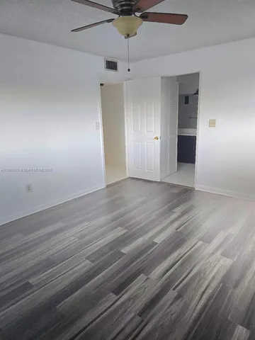 an empty room with wooden floor cabinet and windows