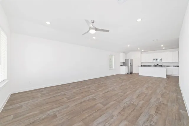 a view of a kitchen with kitchen island a sink wooden floor and a refrigerator