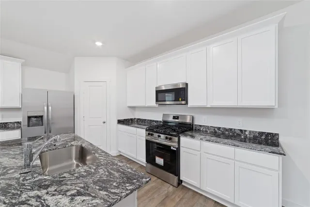 a kitchen with stainless steel appliances granite countertop a sink stove and refrigerator