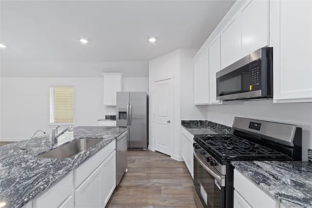 a view of a kitchen island a sink wooden floor and a window