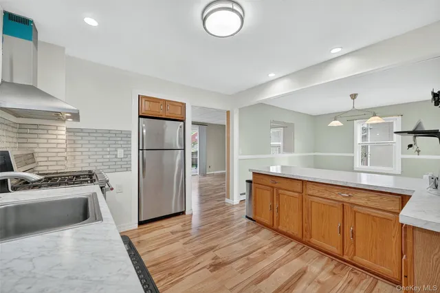 a kitchen with stainless steel appliances granite countertop a sink a stove a refrigerator and cabinets