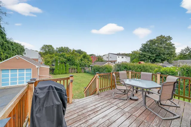 a view of a roof deck with table and chairs a barbeque with wooden floor and fence