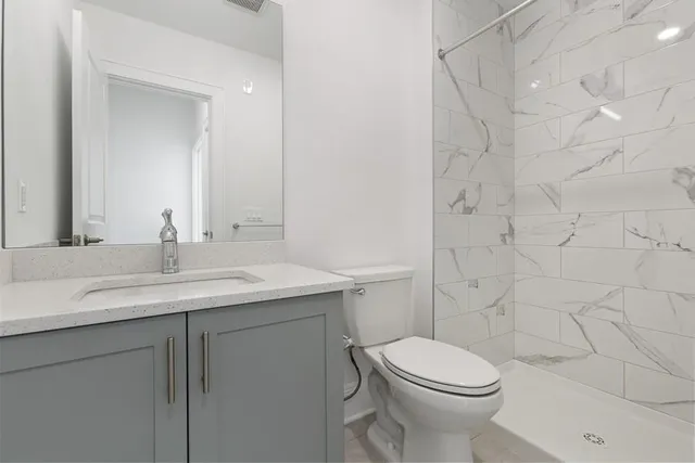 a bathroom with a granite countertop toilet sink and mirror