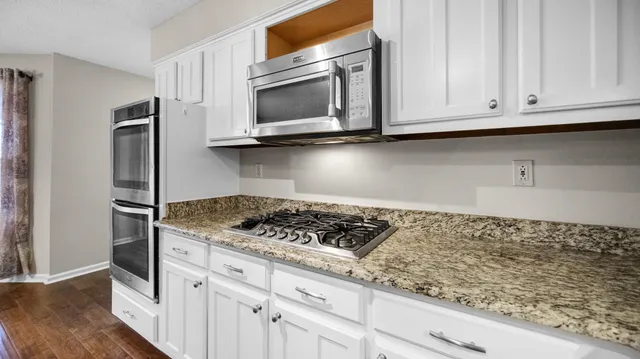 a kitchen with granite countertop white cabinets and stainless steel appliances