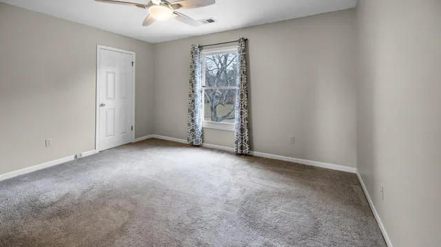 an empty room with a window and a fan