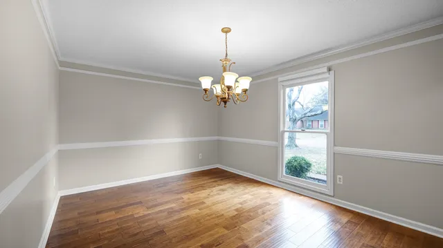 a view of a room with wooden floor and a chandelier