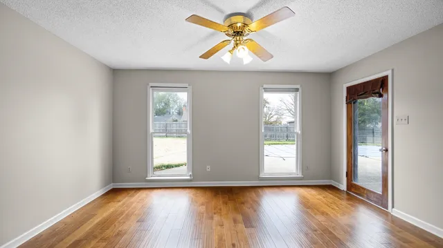 a view of an empty room with window and wooden floor