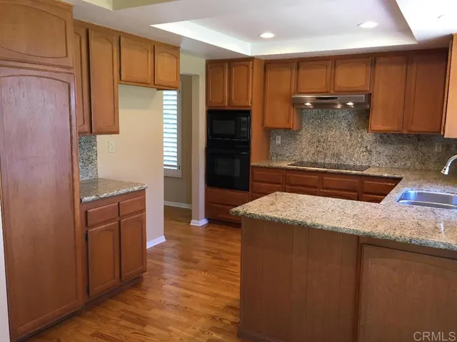 a kitchen with kitchen island granite countertop a refrigerator and wooden cabinets