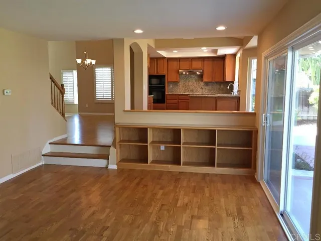 a view of a hallway with wooden floor and chandelier