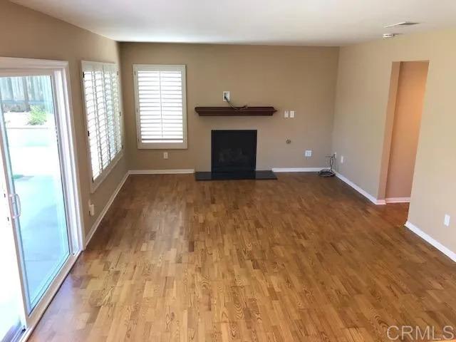 a view of empty room with wooden floor and fireplace