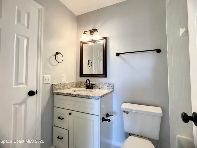 a bathroom with a toilet sink vanity and mirror