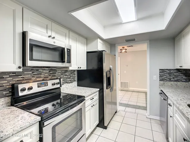 a kitchen with granite countertop a stove microwave and refrigerator