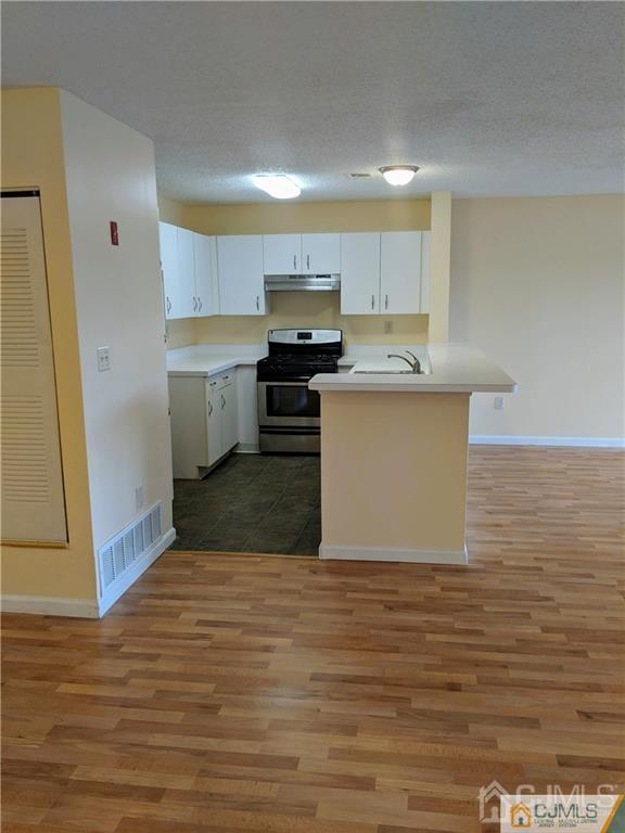 1223 Edpas Road, Unit 1223 New Brunswick, NJ 08901 - Photo 6 of 18 a kitchen with stainless steel appliances a white stove top oven and cabinets