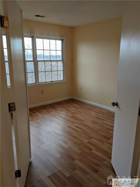 1223 Edpas Road, Unit 1223 New Brunswick, NJ 08901 - Photo 7 of 18 an empty room with wooden floor and windows