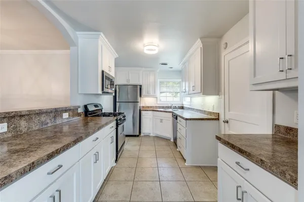 a large kitchen with stainless steel appliances granite countertop a sink counter space cabinets and a large window