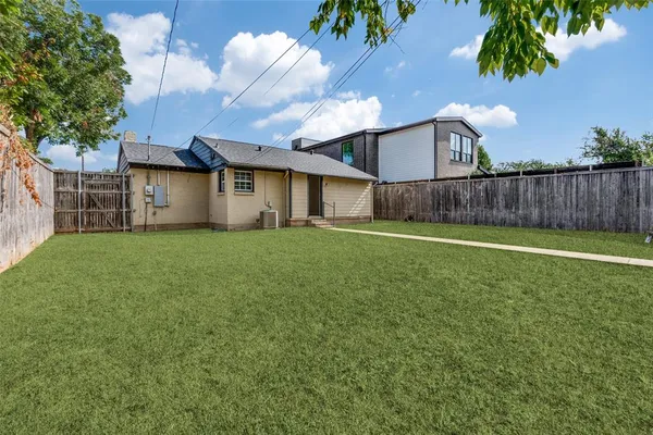 a view of a house with a yard and a large tree