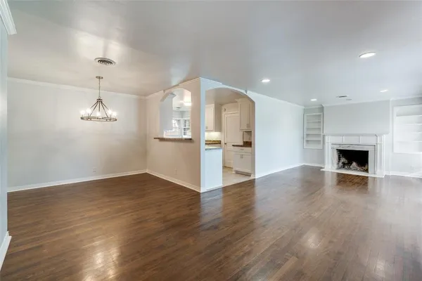 an empty room with wooden floor fireplace and windows