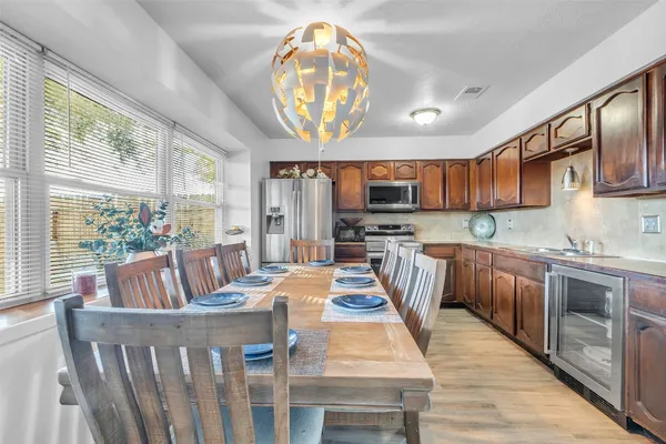 a kitchen with stainless steel appliances kitchen island granite countertop a refrigerator a stove top oven and a dining table with wooden floor