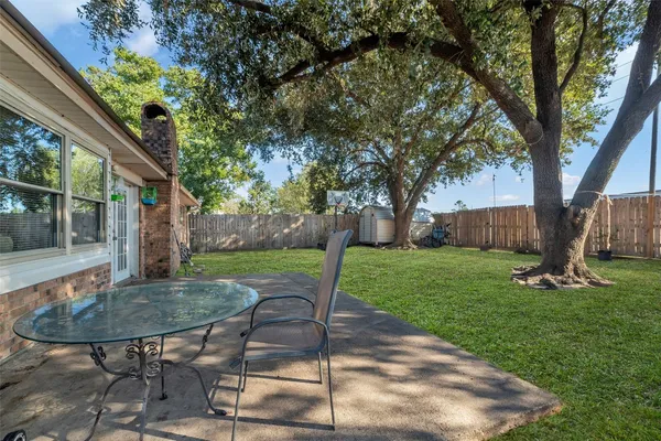 a view of a backyard with table and chairs with a table and a large tree