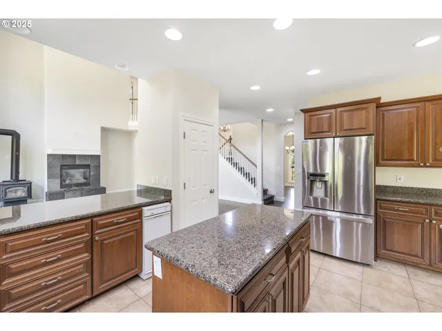 a kitchen with stainless steel appliances granite countertop a refrigerator a sink and wooden cabinets