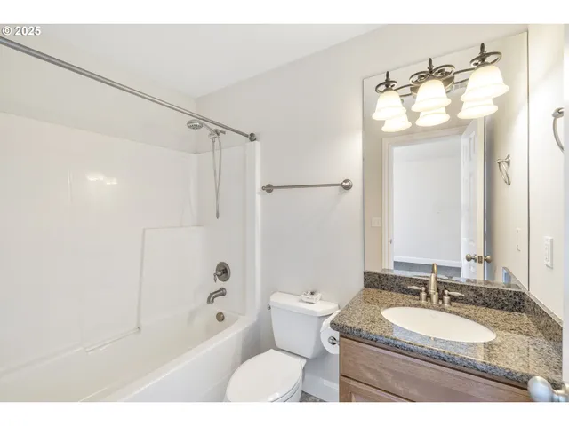 a bathroom with a granite countertop sink mirror toilet and bathtub
