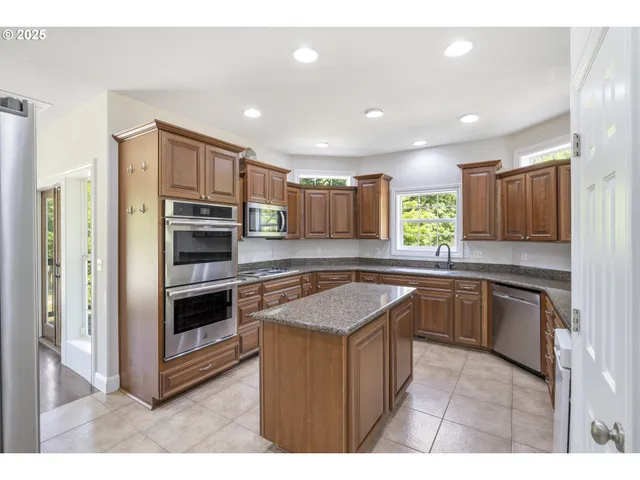 a kitchen with stainless steel appliances granite countertop refrigerator a sink a stove a microwave and island