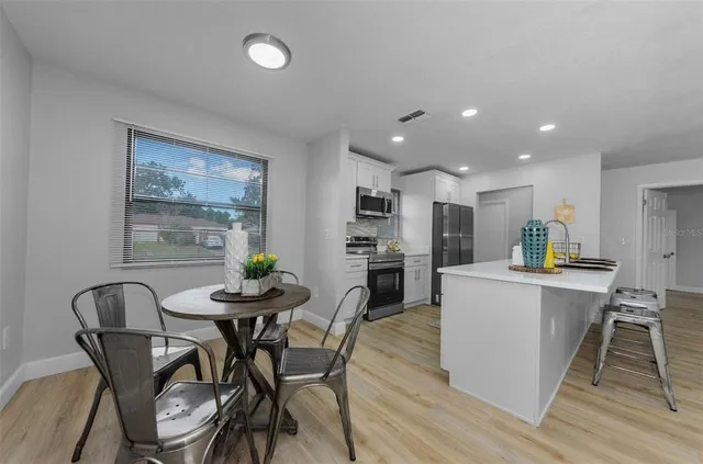 a kitchen with a dining table chairs and wooden floor