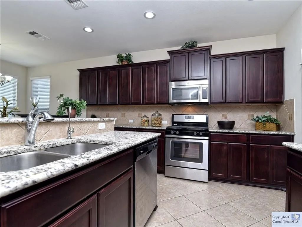 3029 Jacob Lane San Marcos, TX 78666 - Photo 3 of 24 a kitchen with granite countertop stainless steel appliances a stove a sink and a microwave