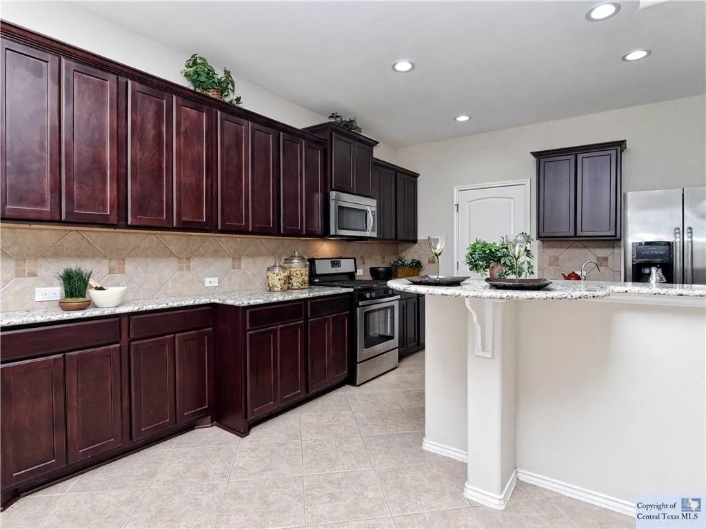 3029 Jacob Lane San Marcos, TX 78666 - Photo 4 of 24 a kitchen with granite countertop wooden cabinets a stove a oven and a granite counter top