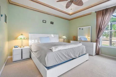 a bedroom with a large bed and a chandelier fan