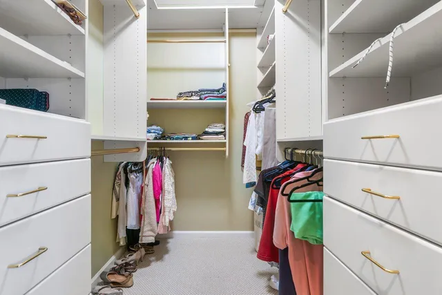 a view of walk in closet with clothes and shoes