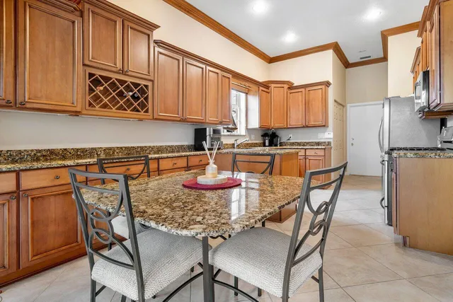 a kitchen with stainless steel appliances granite countertop a table chairs sink and cabinets