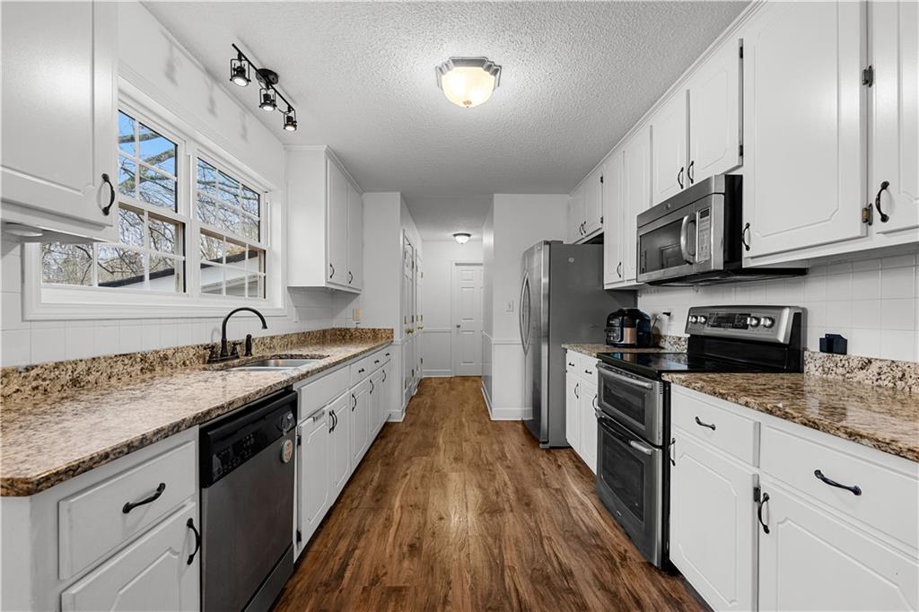 3048 Turner Church Road McDonough, GA 30252 - Photo 12 of 57 a large kitchen with stainless steel appliances granite countertop a lot of counter space and wooden floors