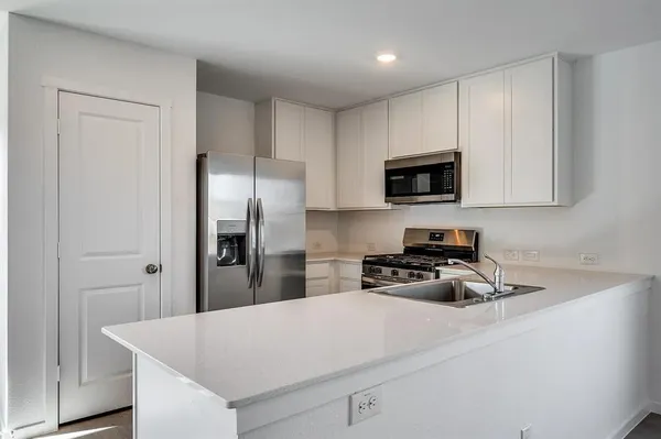 a kitchen with a refrigerator a microwave a sink and cabinets