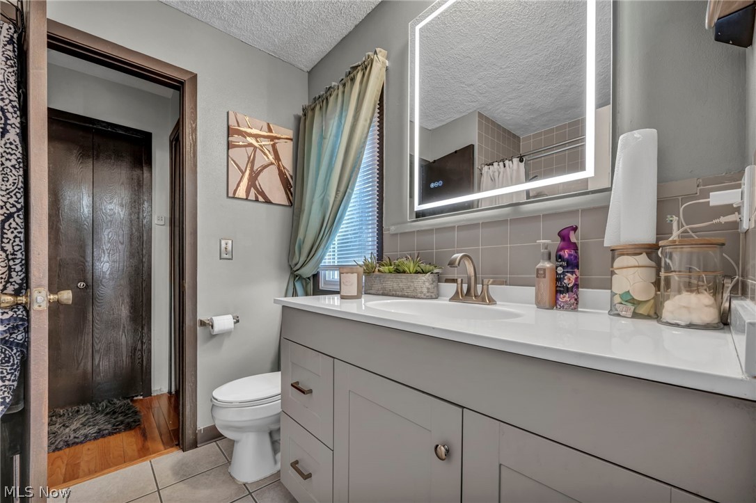 13800 Milo Road Garfield Heights, OH 44125 - Photo 20 of 39 Bathroom featuring vanity, a textured ceiling, decorative backsplash, and light tile patterned flooring