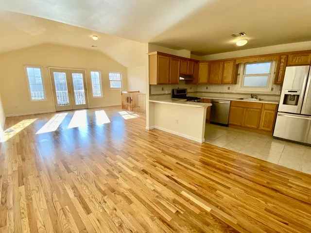 a large kitchen with cabinets wooden floor and stainless steel appliances