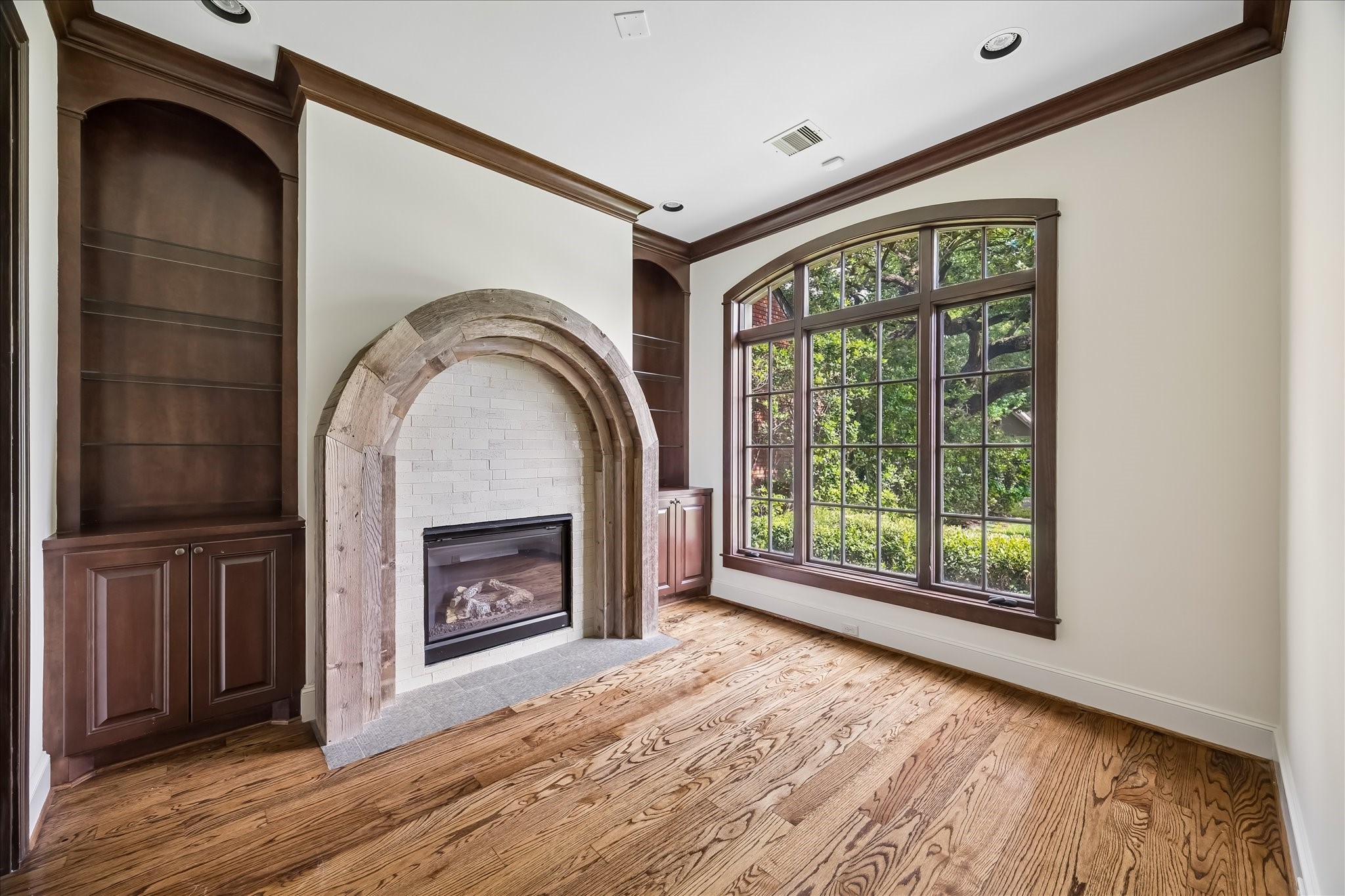 2246 Branard Street Houston, TX 77098 - Photo 6 of 40 Inviting den featuring custom built-ins, dramatic arched fireplace detail, and oversized front-facing windows.