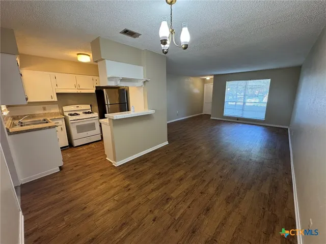 a view of a kitchen with a sink stove cabinets and empty room