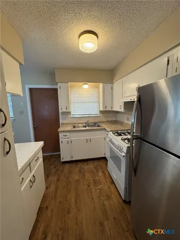 a kitchen with a refrigerator a sink dishwasher and a stove top oven