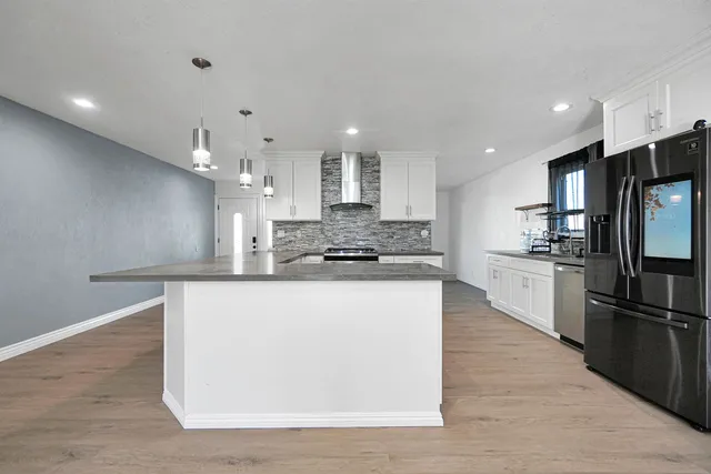 a large kitchen with stainless steel appliances granite countertop a large counter top a sink and a stove